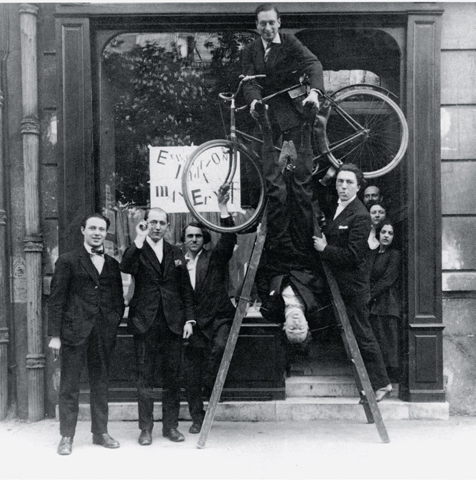 雷内·伊萨姆（René Hilsum），本杰明·佩雷 （Benjamin Péret）, 赛尔日·沙尔舒尔（Serge Charchoune）, 菲利浦·苏波（Philippe Soupault）（骑自行车者）, 雅克·雷高（Jacques Rigaut） (倒挂者)，以及安德烈·布勒东（André Breton）在“达达马克思•恩斯特”展览开幕上， Au Sans Pareil画廊, 巴黎，1921年5月2日.