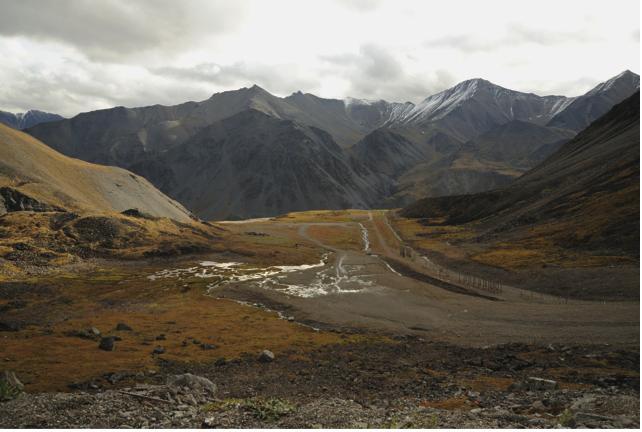 输油管道最高点是Atigun Pass。在这里，在这里，输油管在密封的不锈钢中，在地下延伸八里地，密封的不锈钢盒保护它免于受到山崩的威胁。