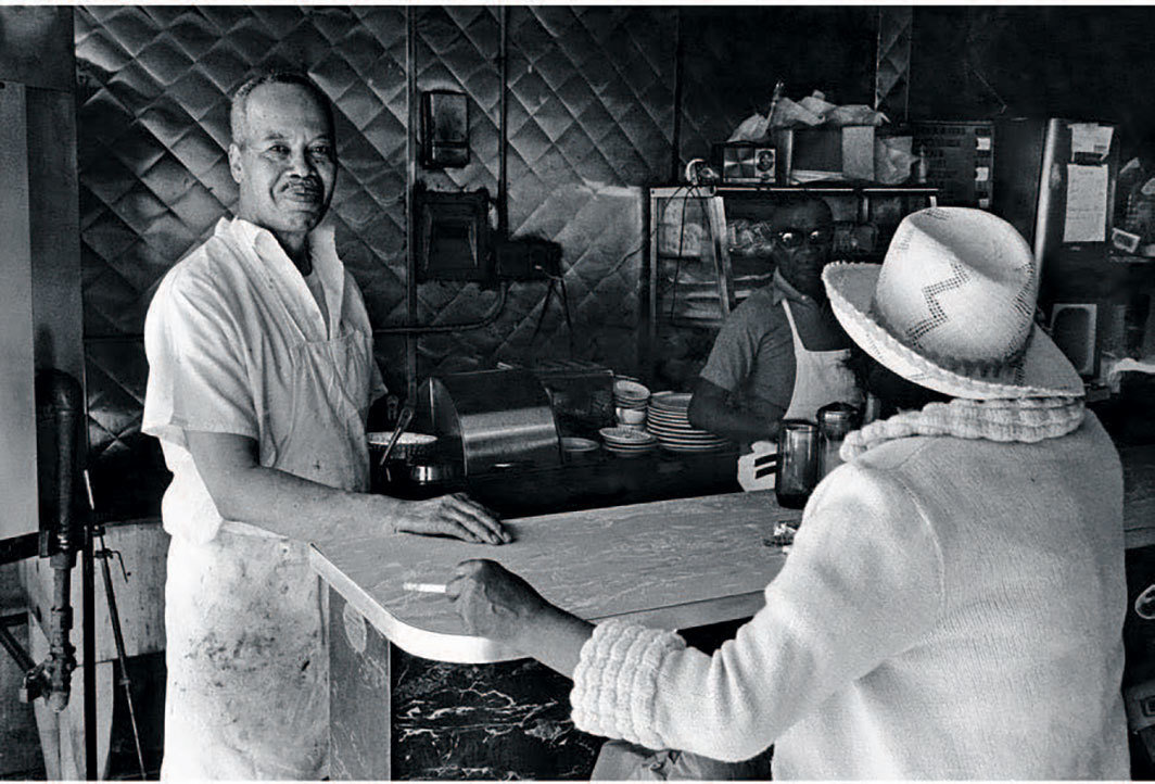 达伍德·贝，《摩尔先生的烧烤店，哈莱姆区，纽约》（Mr. Moore’s Bar-B-Que, Harlem, NY），1976，黑白银盐照片，  8 × 11 7⁄8". 来自“美国哈莱姆区”系列，1975-79.