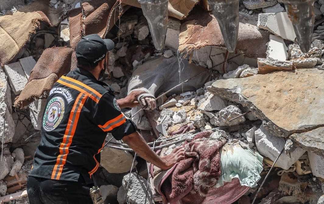 巴勒斯坦人的尸体被从以色列军队炮轰后倒塌的楼房的瓦砾堆里拉出，2021年5月16日. 摄影：Mohammed Zaanoun.