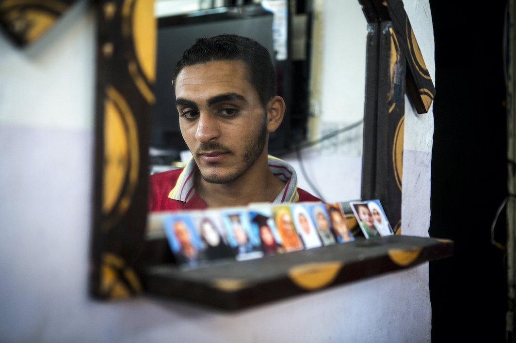 Ala Balata，18岁，他面前摆放的是他在以色列对加沙地带Jabaliah难民营轰炸中丧生的家人的照片，2014年9月14日. 摄影：安·帕克.