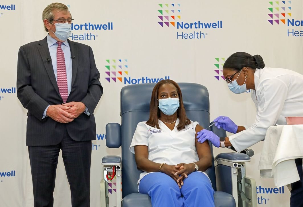 Northwell的首席执行官迈克尔·多林（Michael Dowling ）注视着全美第一位辉瑞Covid疫苗接种者、重症监护护士桑德拉·林赛接受疫苗接种. 图片：Northwell Health.