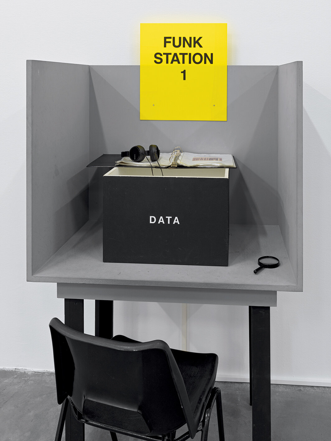 蕾妮·格林，《进口/出口放克办公室》（局部），1992-93，混合媒介，金属层架、书籍、杂志、报纸、收藏品、BETA录像带、25小时数字化影像、两台显示器、一个影像投影、磁带、声音、亚克力标志、四个木制结构、四个架子上的亚克力标志、四台磁带播放器、三十个印有橡皮章文字的木牌。展览现场，苏黎世米格罗斯博物馆（Migros Museum），2022. 摄影：Stefan Altenburger.