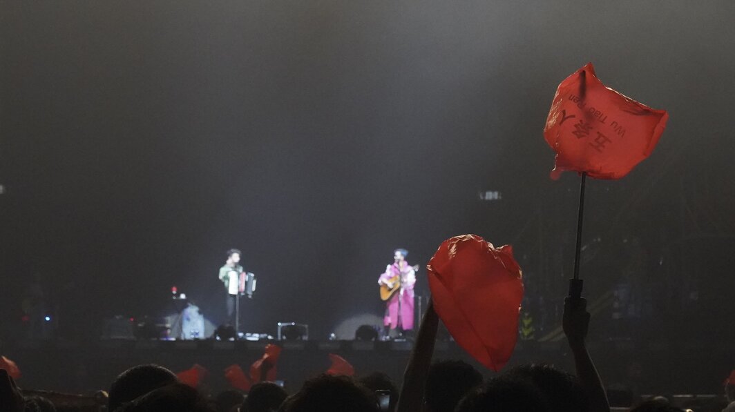 演唱会现场，粉丝高举红色塑料袋.