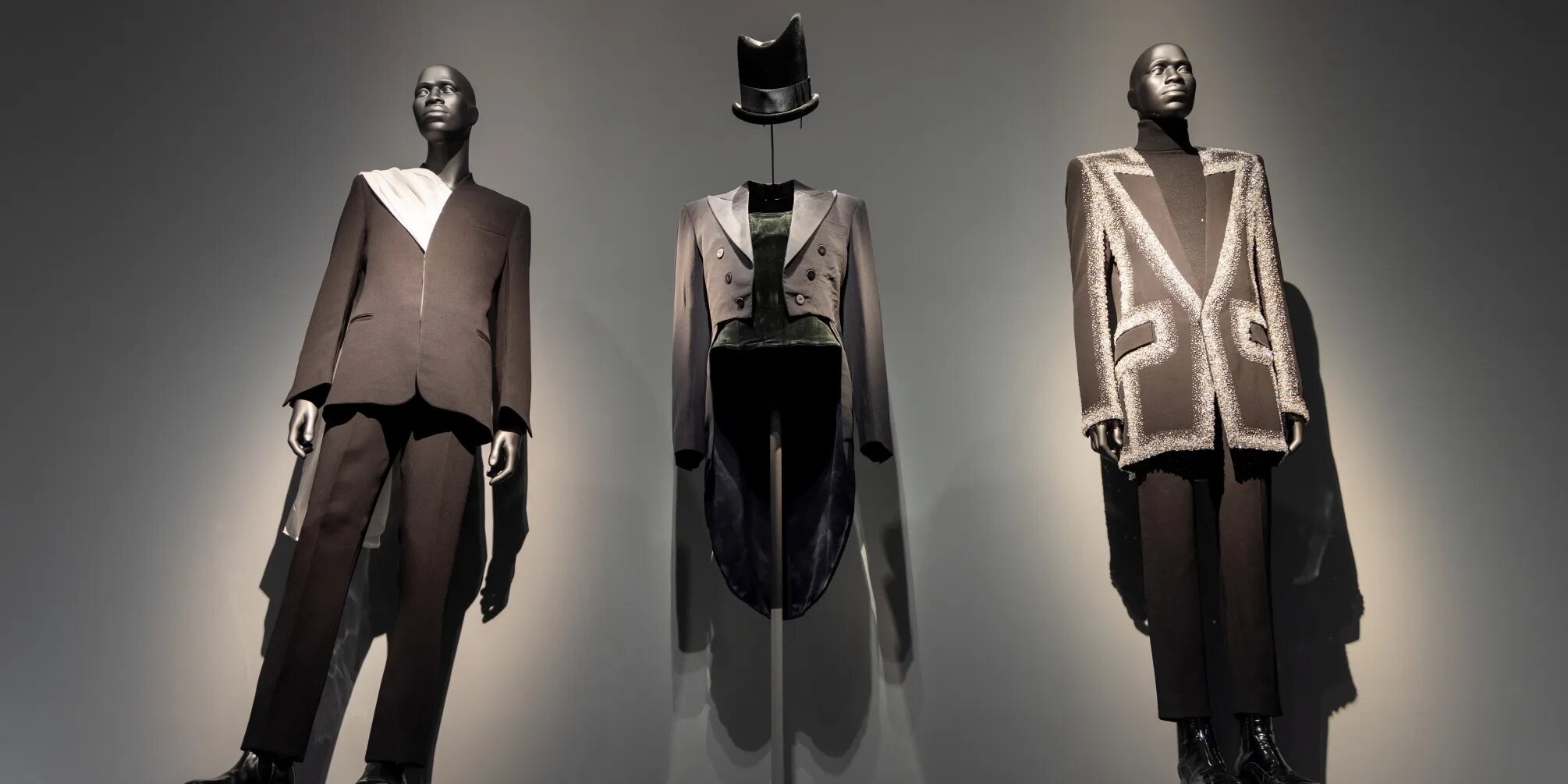 “超凡风范：定制黑人时尚”展览现场，2025，纽约大都会艺术博物馆. 左起: 马克西米利安·戴维斯（Maximilian Davis），《合奏》，2023；菲利普·特雷西（Philip Treacy），《帽子》，2020-21；奥利维尔·鲁斯汀（Olivier Rousteing），《西装》，2024-25. 所有照片提供: 大都会艺术博物馆. 