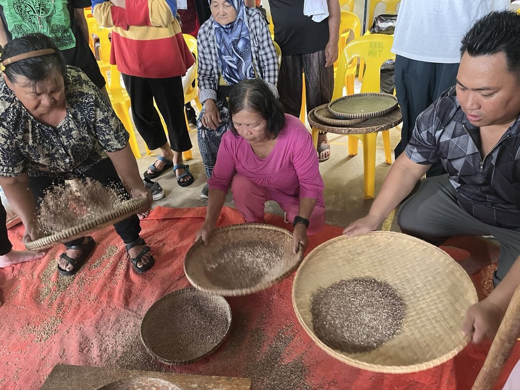 村民展示传统稻米分级方法.