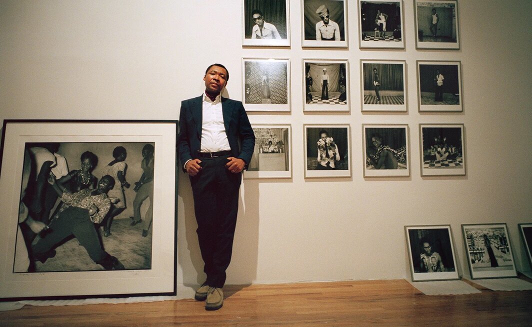 奥奎·恩维佐与他策划的展览“短暂的世纪：1945-1994年非洲独立与解放运动”中选用的马利克·西迪贝（Malick Sidibé）摄影作品，纽约MoMA PS1，2002年2月6日. 图片提供：Edward Keating/The New York Times.