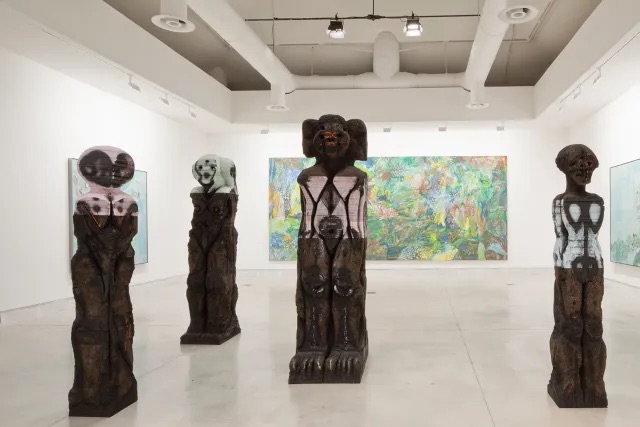 “全世界的未来”展览现场，2015，威尼斯中央展馆. 前景：胡玛·巴巴（Huma Bhabha）作品，2015. 背景：艾米莉·坎·恩瓦瑞（Emily Kame Kngwarreye），《地球的创造》，1994. 出自第五十六届威尼斯双年展. 摄影：Alessandra Chemollo.